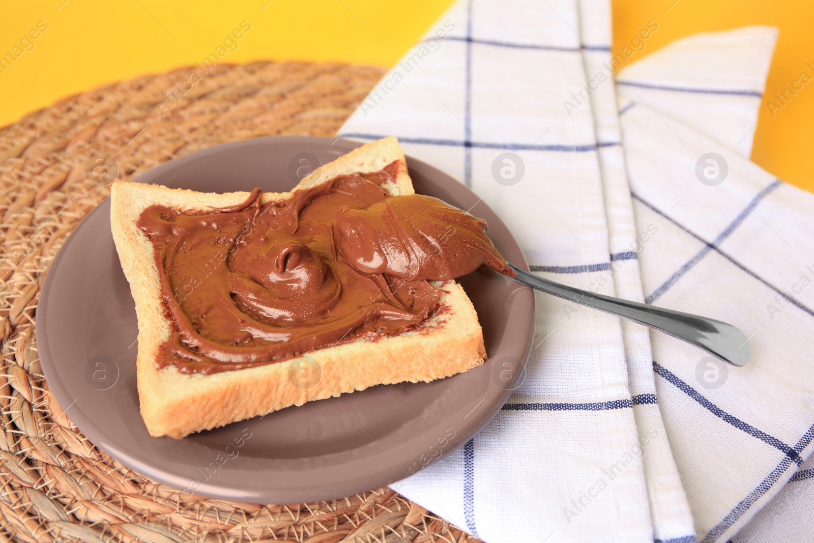 Photo of Tasty toast with chocolate paste on yellow background