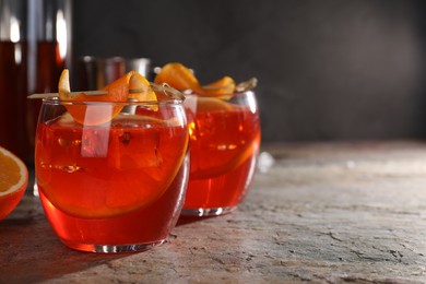 Photo of Aperol spritz cocktail, ice cubes and orange slices in glasses on grey textured table, closeup. Space for text