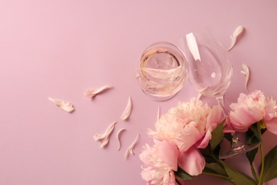 Photo of Glasses with rose wine and beautiful peonies on pink background, flat lay