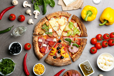 Photo of Flat lay composition with slices of different delicious pizzas on grey table