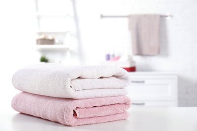 Photo of Stack of fresh towels on table in bathroom. Space for text