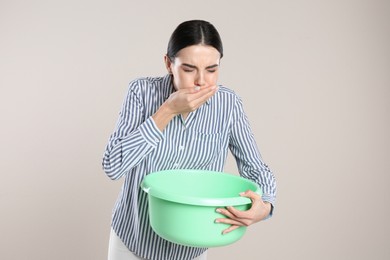 Photo of Woman with basin suffering from nausea on beige background. Food poisoning