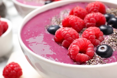 Photo of Delicious acai smoothie with raspberries and chia seeds in bowl, closeup