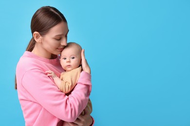 Photo of Mother with her cute baby on light blue background, space for text