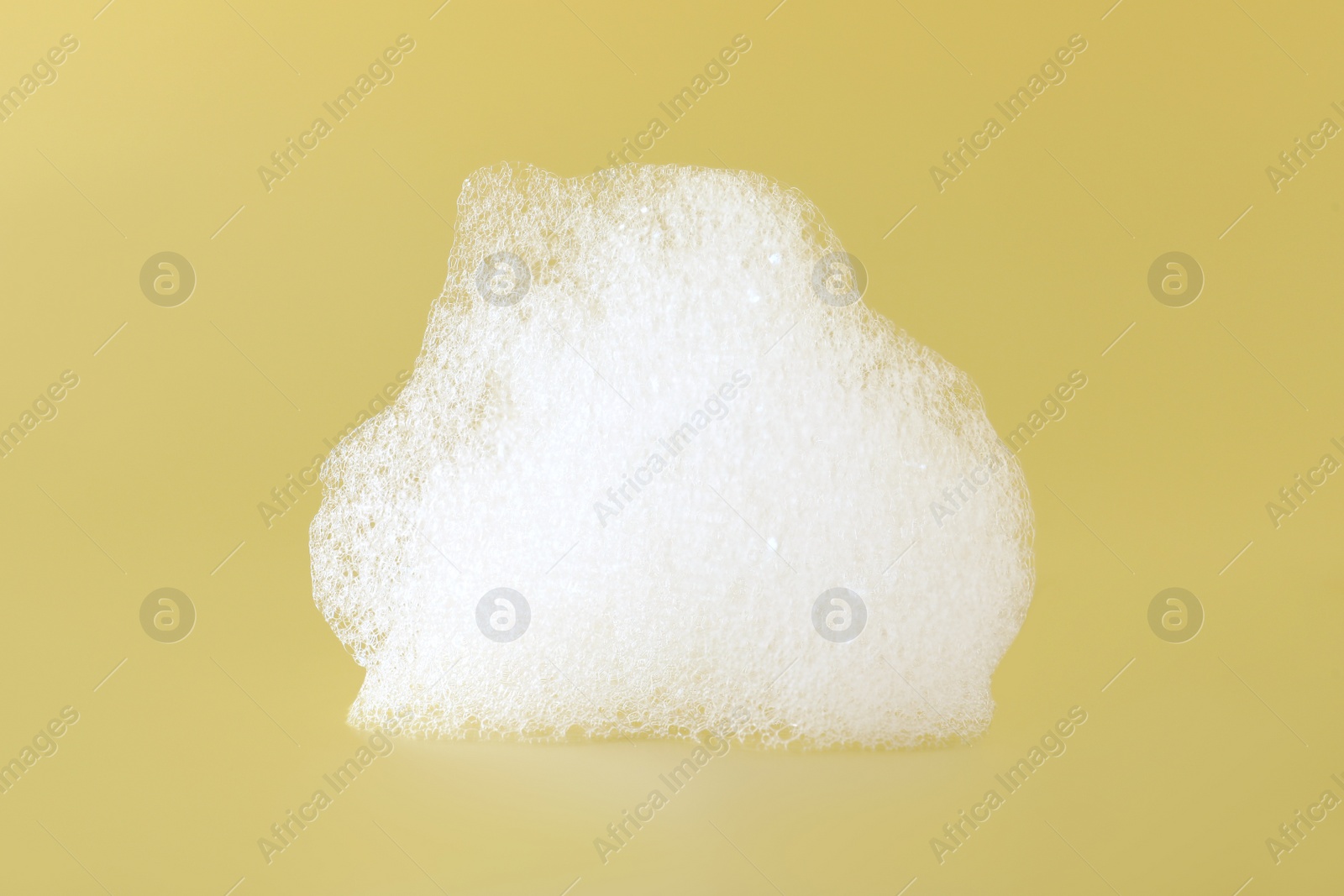Photo of Drop of fluffy bath foam on pale orange background