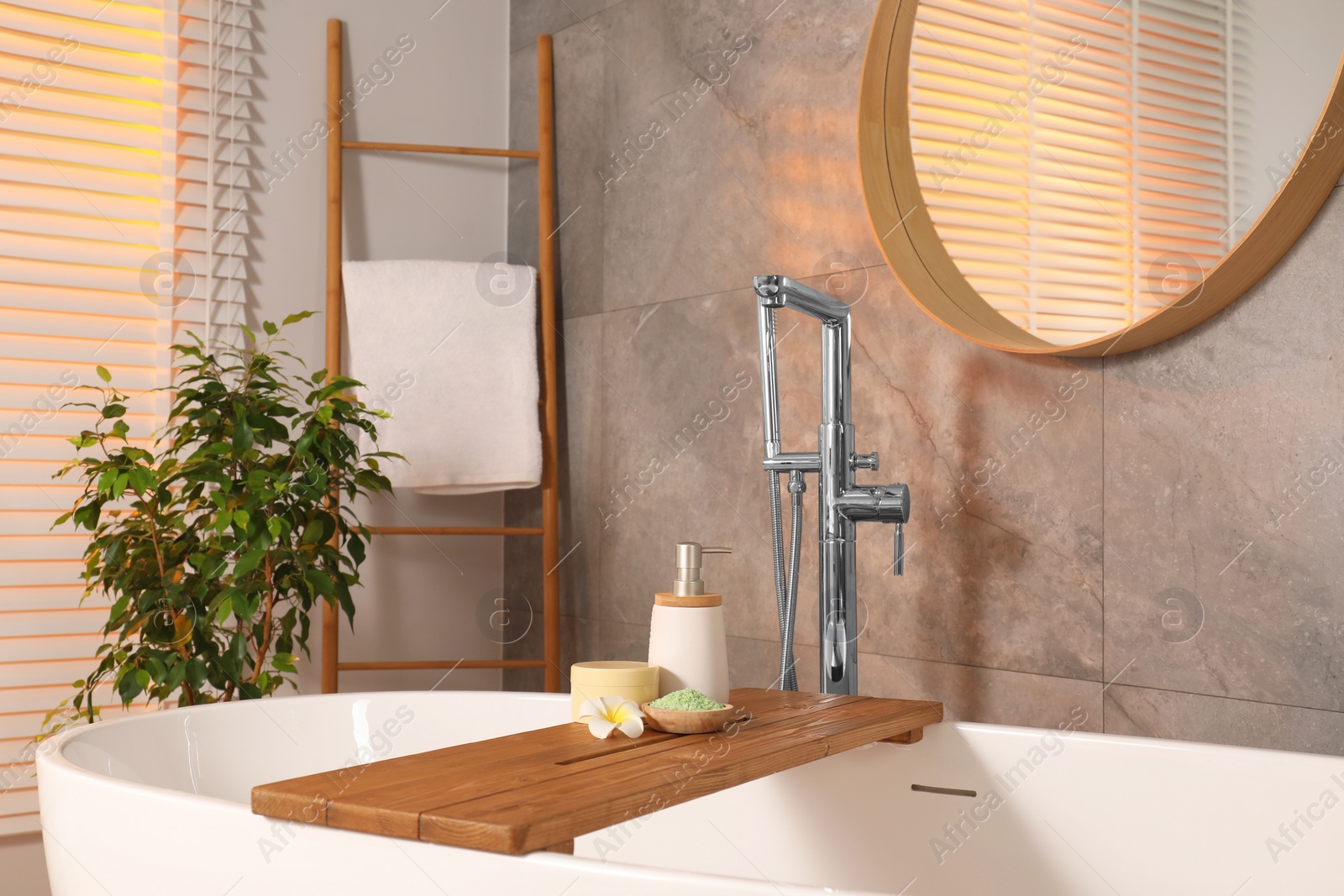 Photo of Spa products and beautiful flower on wooden tub tray in bathroom