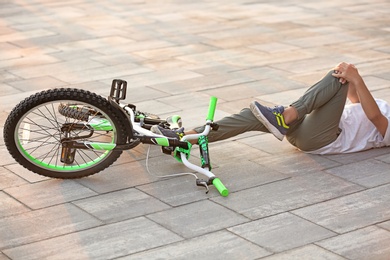 Photo of Little boy fallen off his bicycle on street, closeup