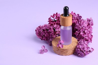 Photo of Bottle with essential oil and lilac flowers on violet background, space for text