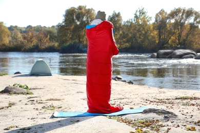 Photo of Male camper in sleeping bag on wild beach