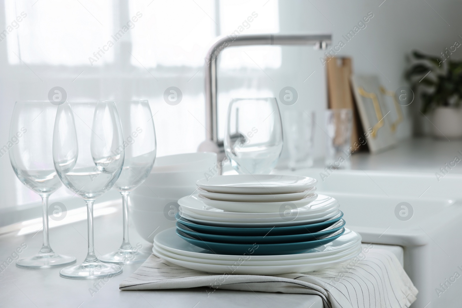 Photo of Different clean dishware and glasses on countertop near sink in kitchen