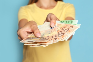 Photo of Woman with Euro banknotes on blue background, closeup