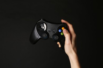 Woman with game controller on black background, closeup
