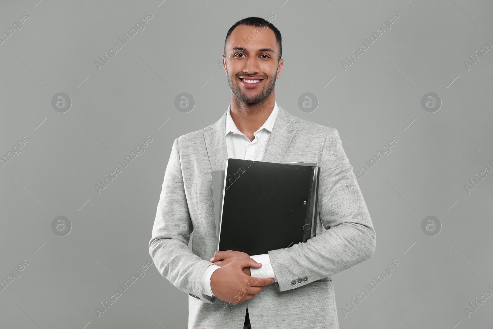 Photo of Young businessman with folders on grey background