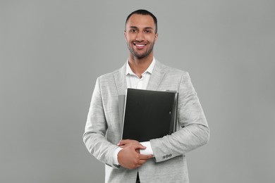 Young businessman with folders on grey background
