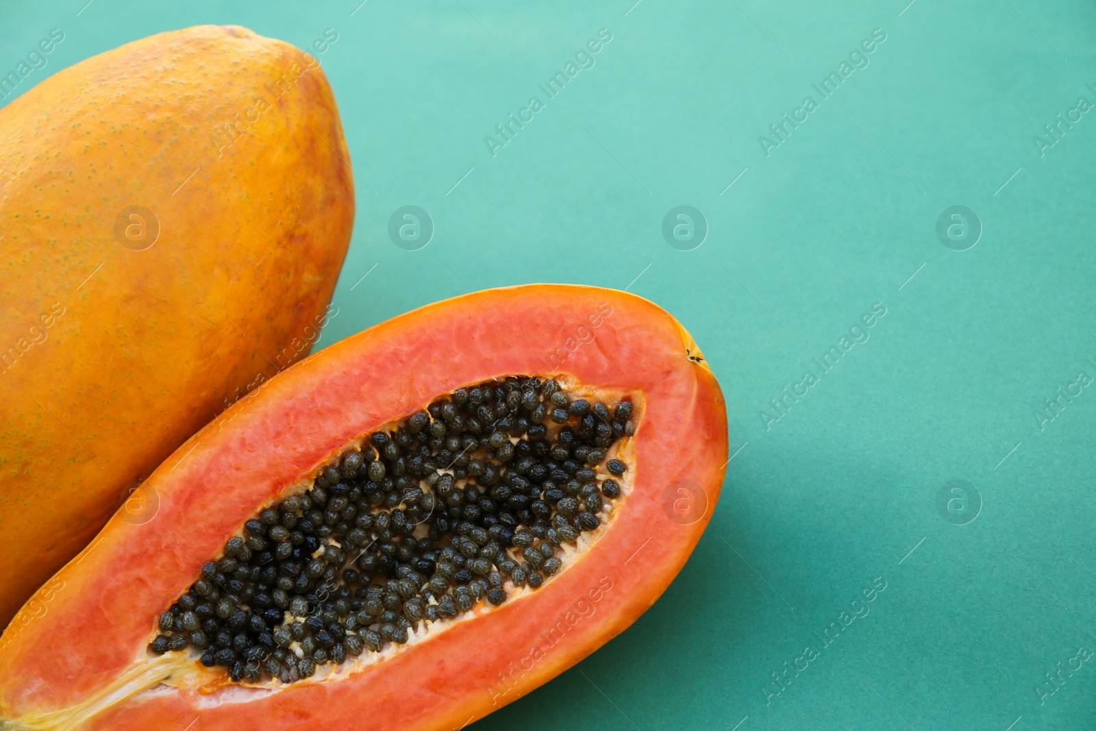 Photo of Fresh ripe cut and whole papaya fruits on light blue background, closeup. Space for text