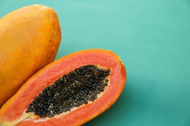 Photo of Fresh ripe cut and whole papaya fruits on light blue background, closeup. Space for text