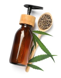 Photo of Bottle of hemp cosmetics with green leaves and seeds isolated on white, top view