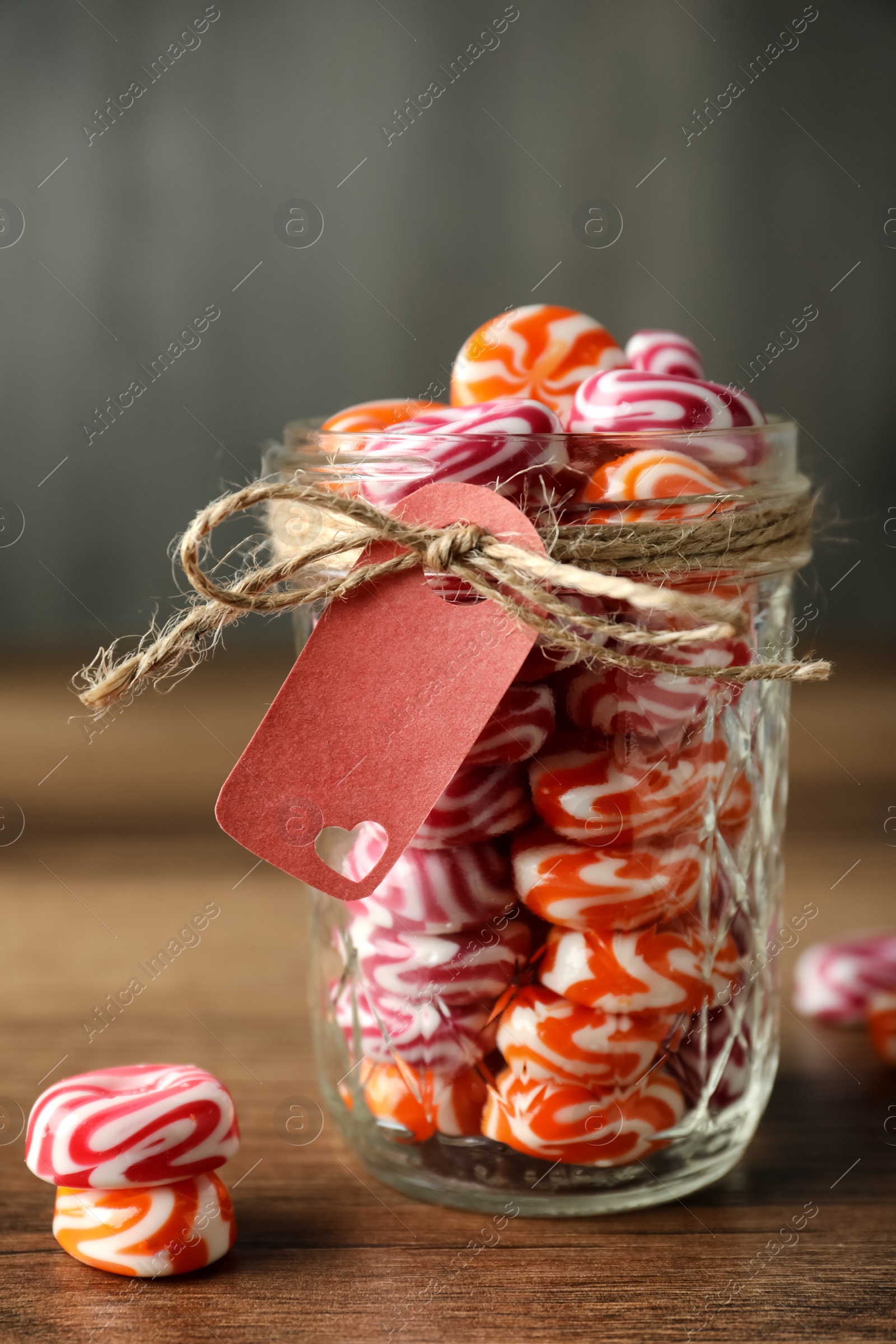 Photo of Colorful hard candies in glass jar on wooden table