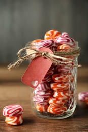 Photo of Colorful hard candies in glass jar on wooden table