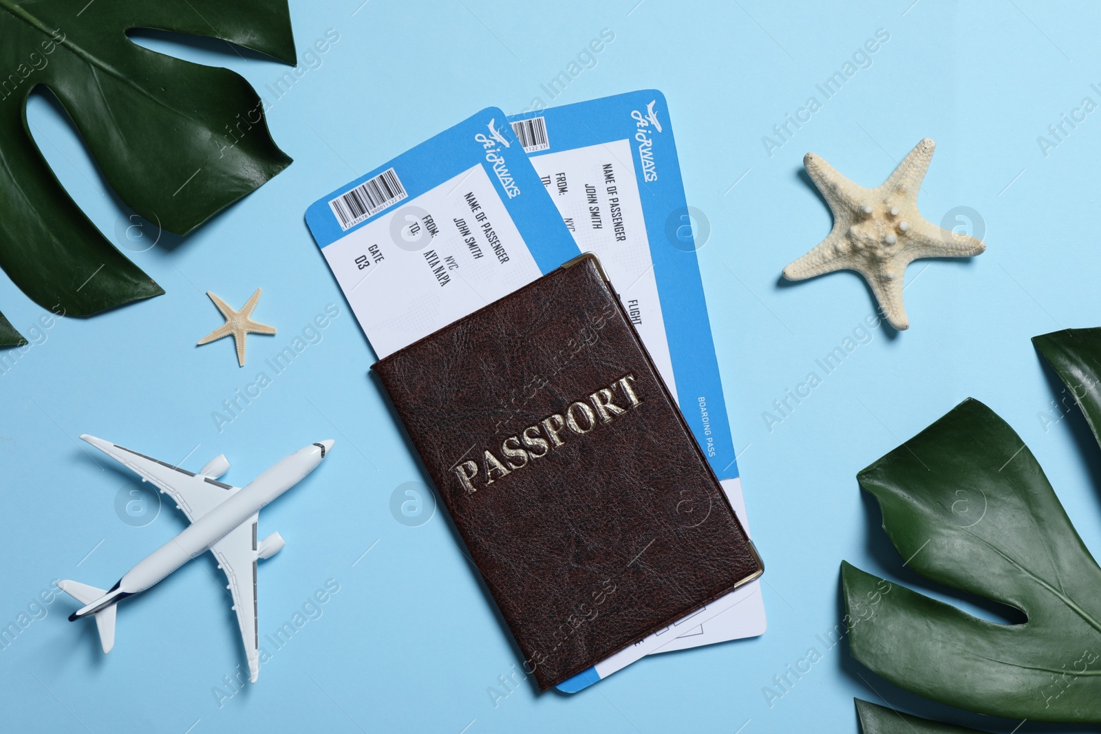 Photo of Passport with tickets, airplane model, starfishes and tropical leaves on light blue background, flat lay. Time to travel