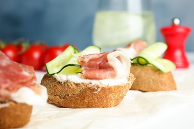 Photo of Tasty bruschettas with prosciutto served on table