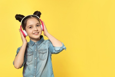 Photo of Cute girl enjoying music in headphones on color background. Space for text