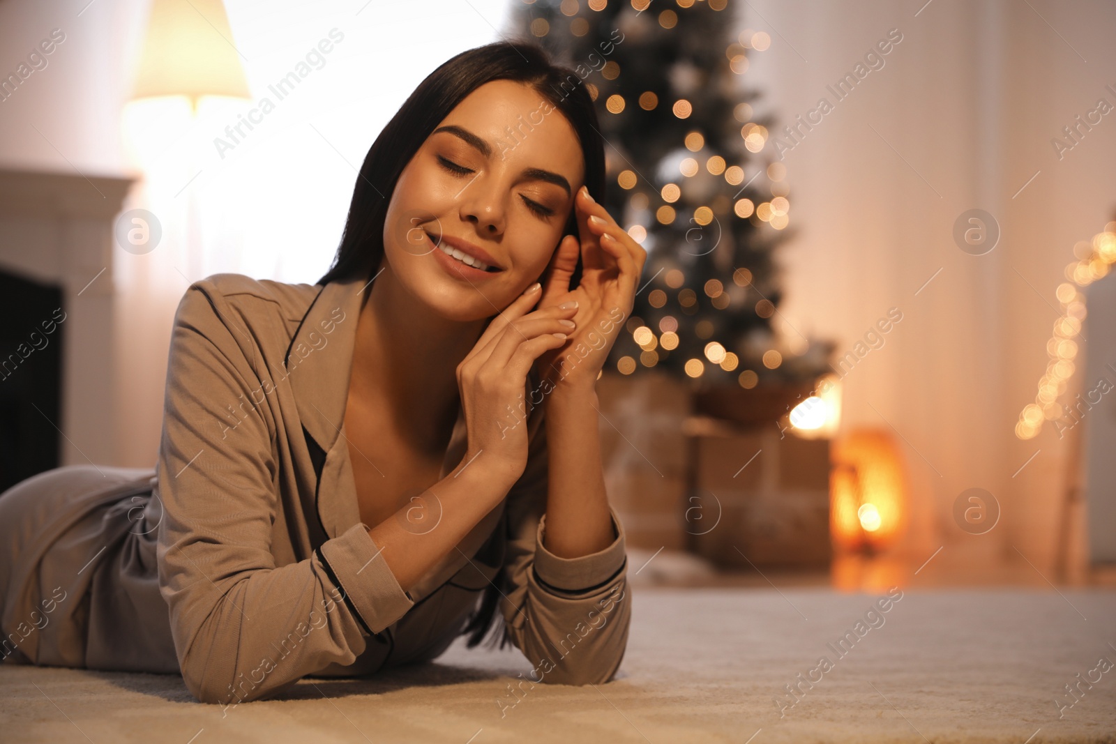 Photo of Young woman on carpet at home, space for text. Christmas celebration