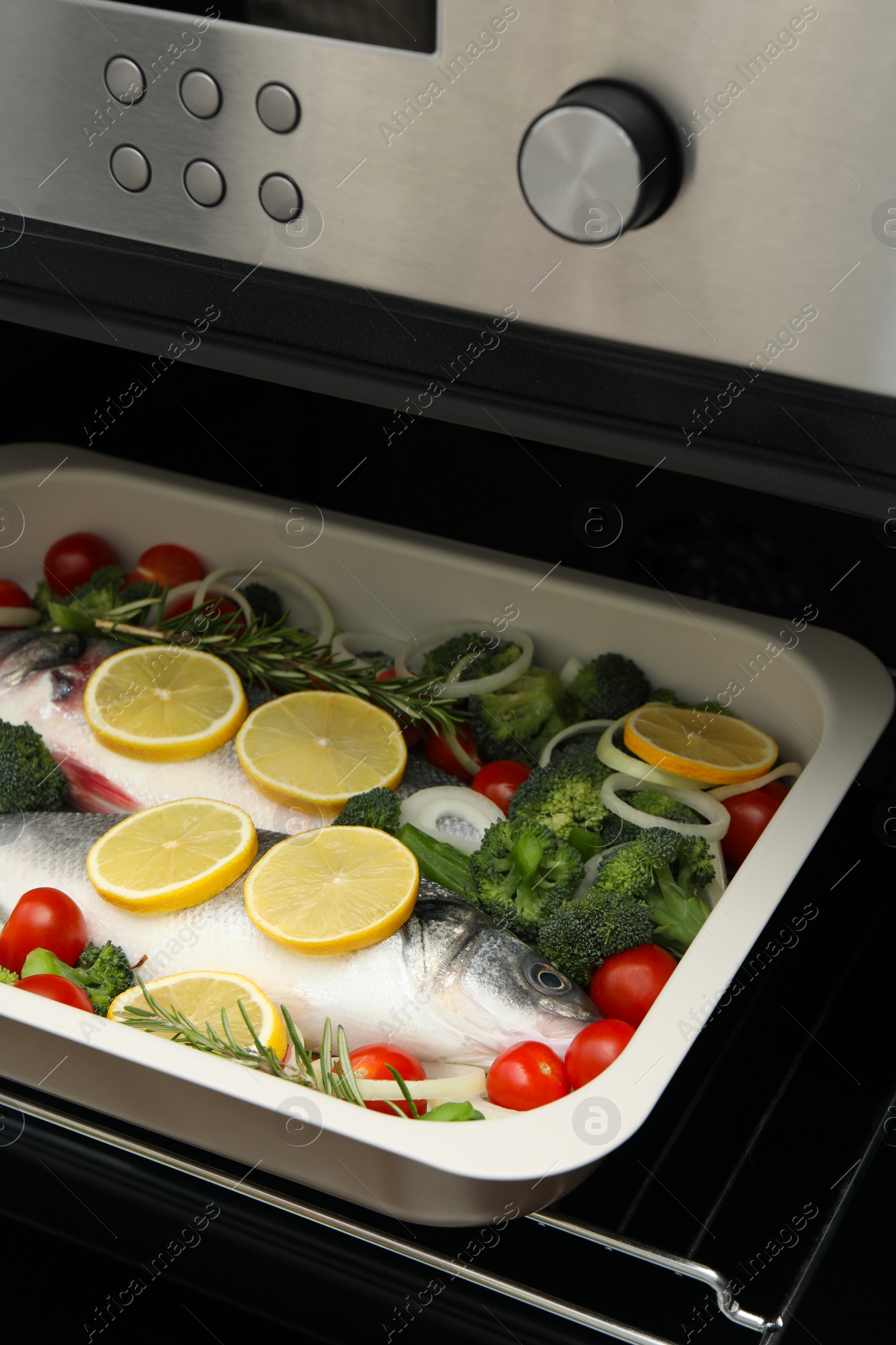 Photo of Raw fish with vegetables and lemon in baking dish into oven