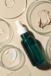 Photo of Bottle of cosmetic serum and petri dishes with samples on beige background, flat lay