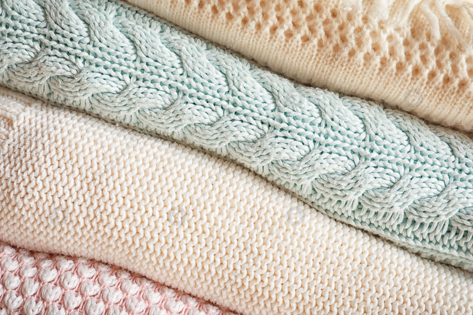 Photo of Stack of warm knitted clothes as background