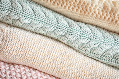 Photo of Stack of warm knitted clothes as background