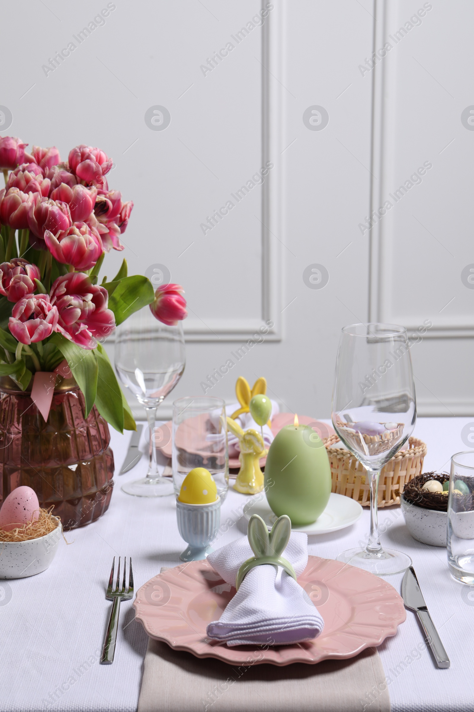 Photo of Festive table setting with napkin ring in shape of bunny ears. Easter celebration