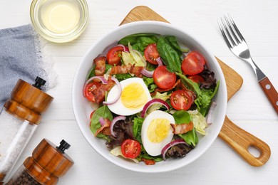 Delicious salad with boiled egg, bacon and vegetables served on white wooden table, flat lay