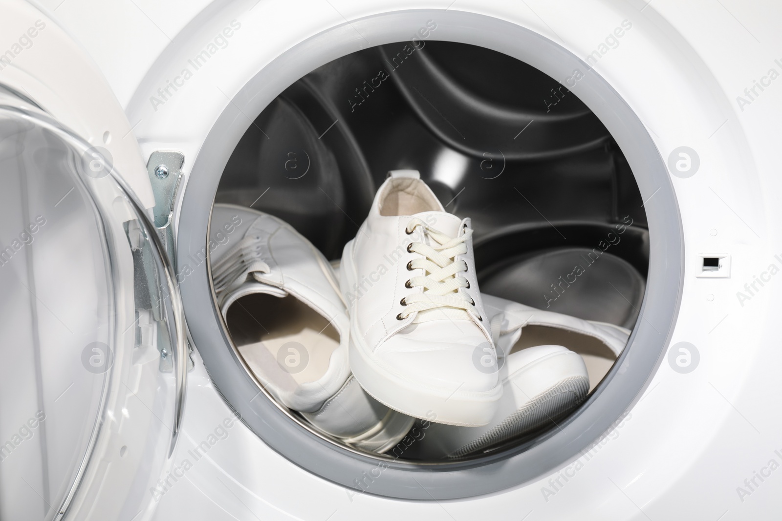 Photo of Stylish clean sneakers inside modern washing machine