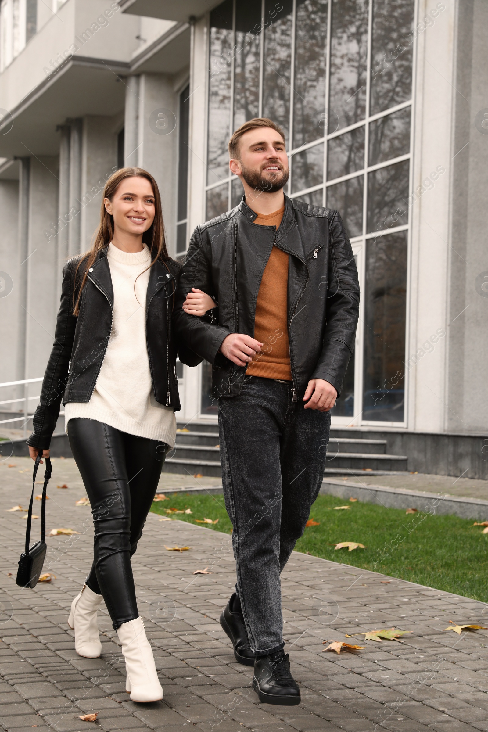 Photo of Happy couple wearing stylish leather jackets on city street. Autumn walk