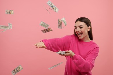 Happy woman throwing money on pink background