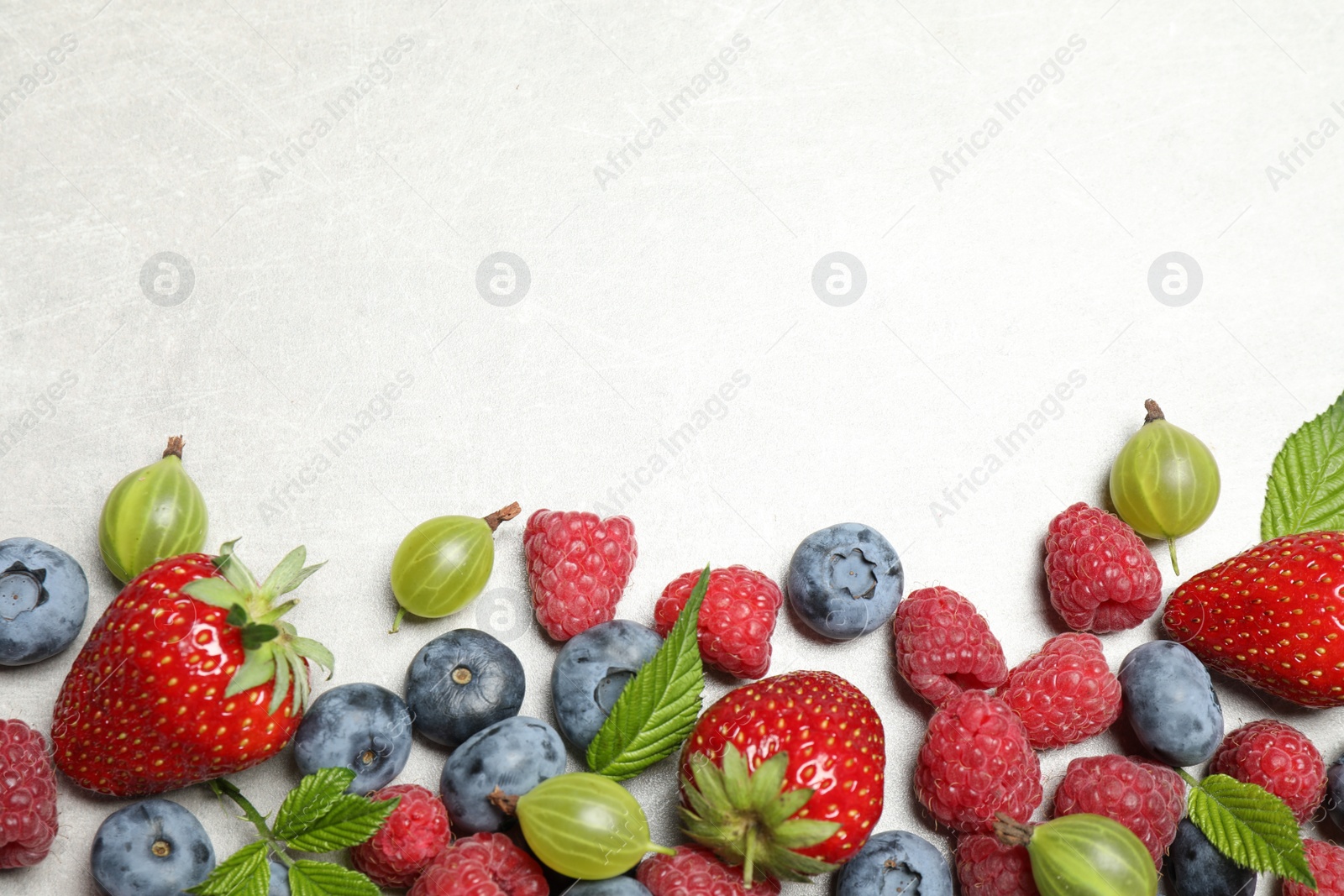 Photo of Mix of fresh berries on light table, flat lay. Space for text