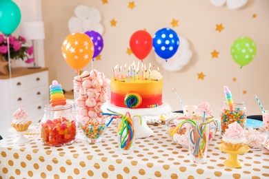 Photo of Table with birthday cake and delicious treats indoors