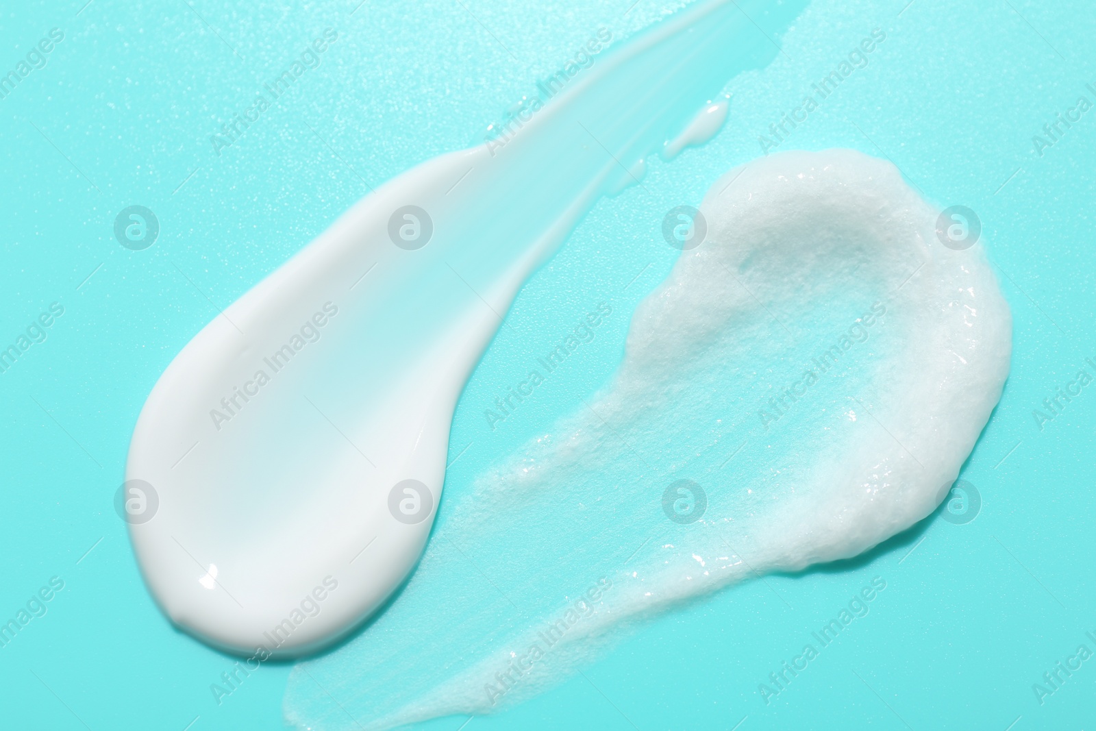 Photo of Samples of face cream on light blue background, top view