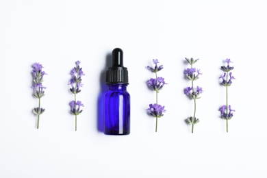 Photo of Bottle of essential oil and lavender flowers on white background, flat lay