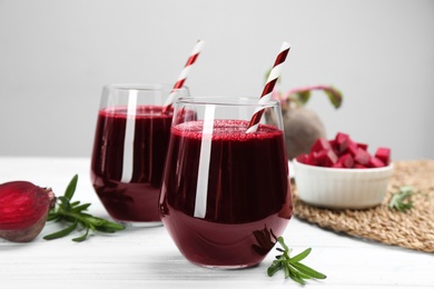 Fresh beet juice and raw vegetable on white wooden table