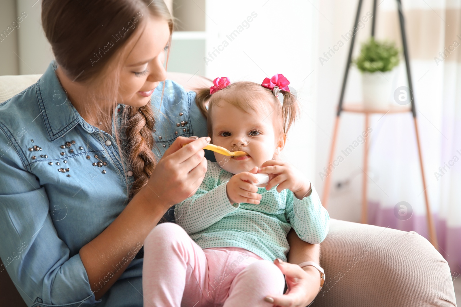 Photo of Caring mother feeding her cute little baby with healthy food at home