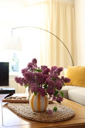 Photo of Beautiful fragrant lilac flowers in vase on table at home