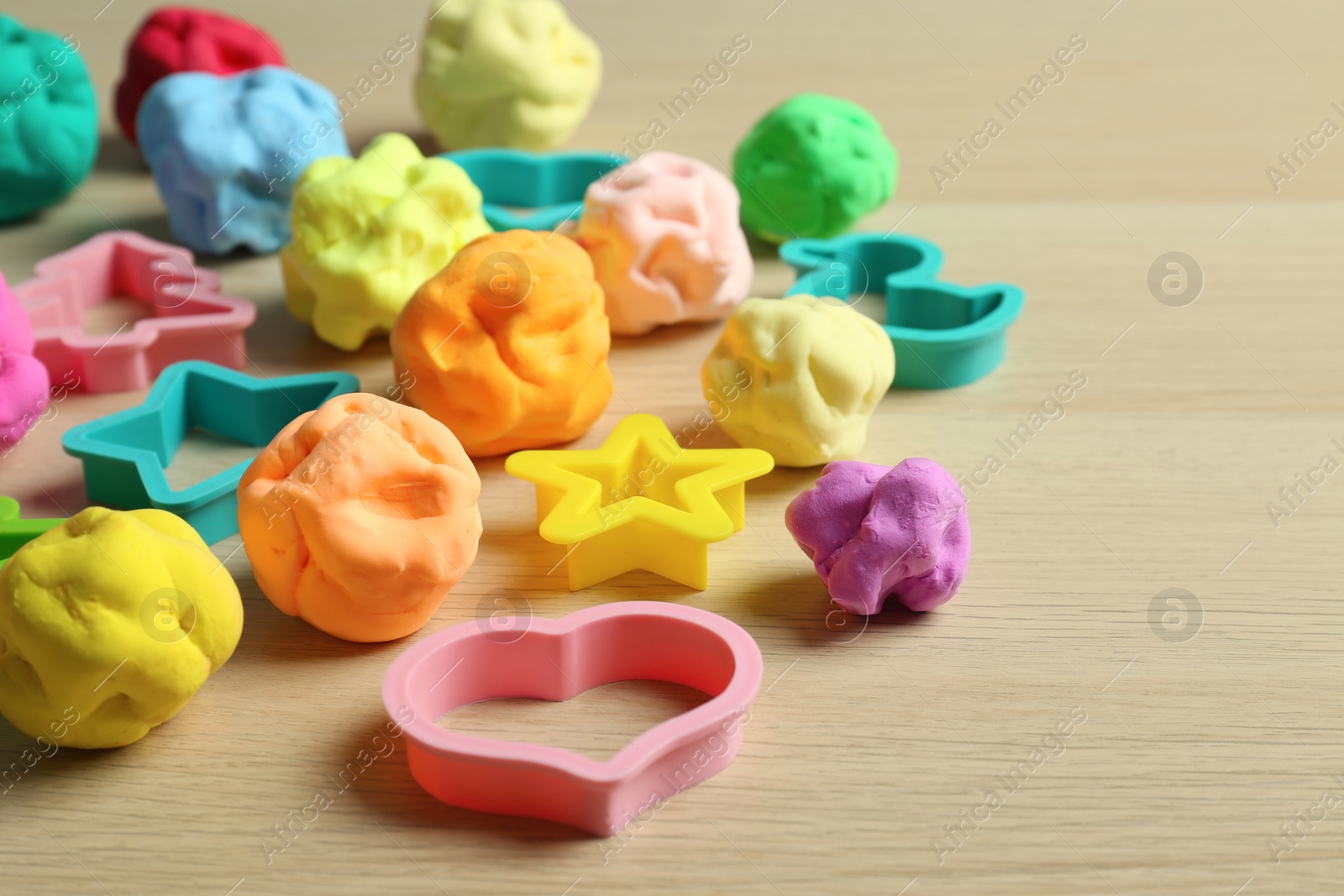 Photo of Different color play dough with molds on wooden table
