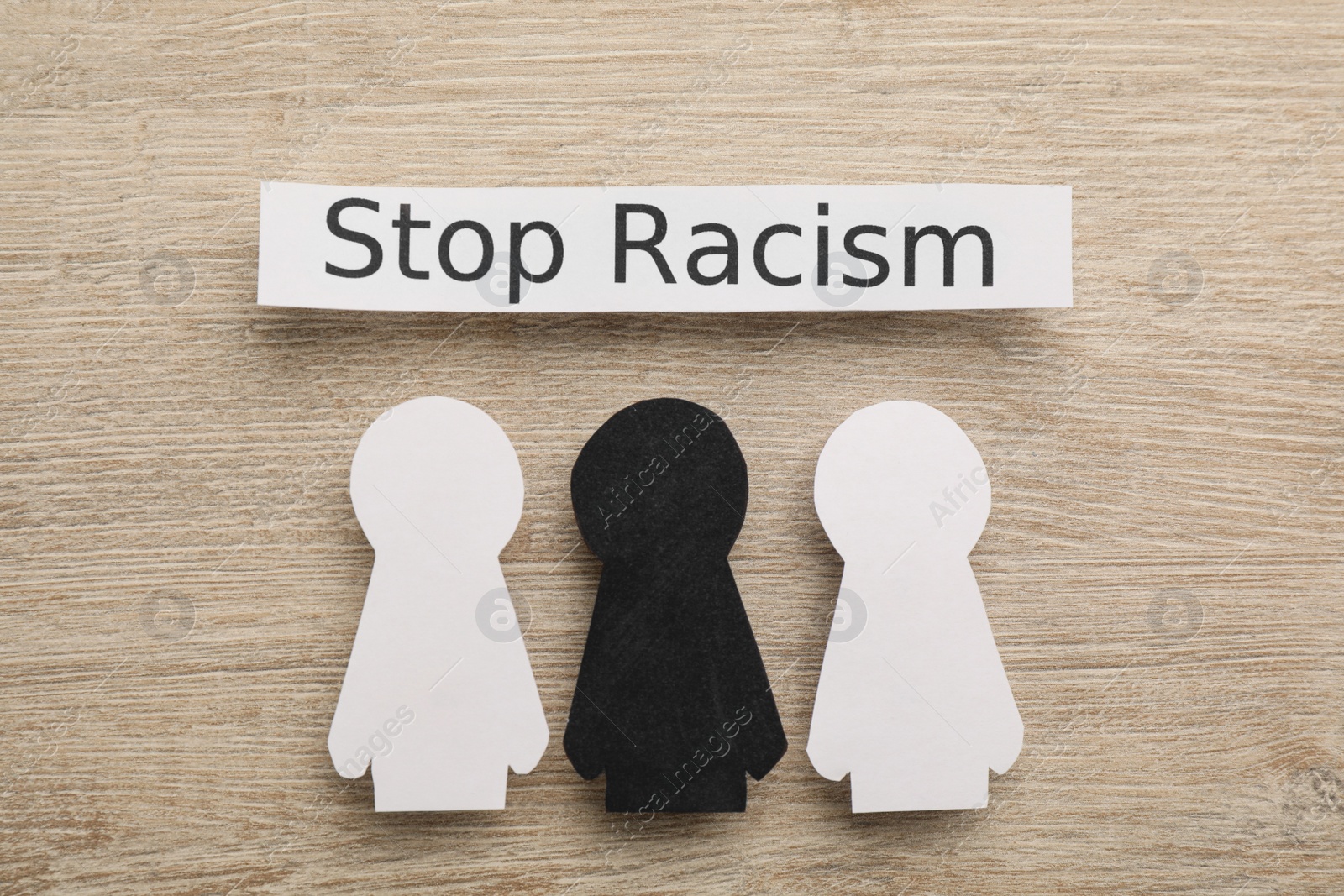 Photo of Phrase Stop Racism and paper figures on wooden table, flat lay