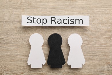 Phrase Stop Racism and paper figures on wooden table, flat lay