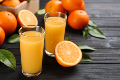 Photo of Delicious orange juice and fresh fruits on black wooden table