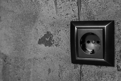 Closeup view of modern power socket on grey wall, space for text. Electrical supply
