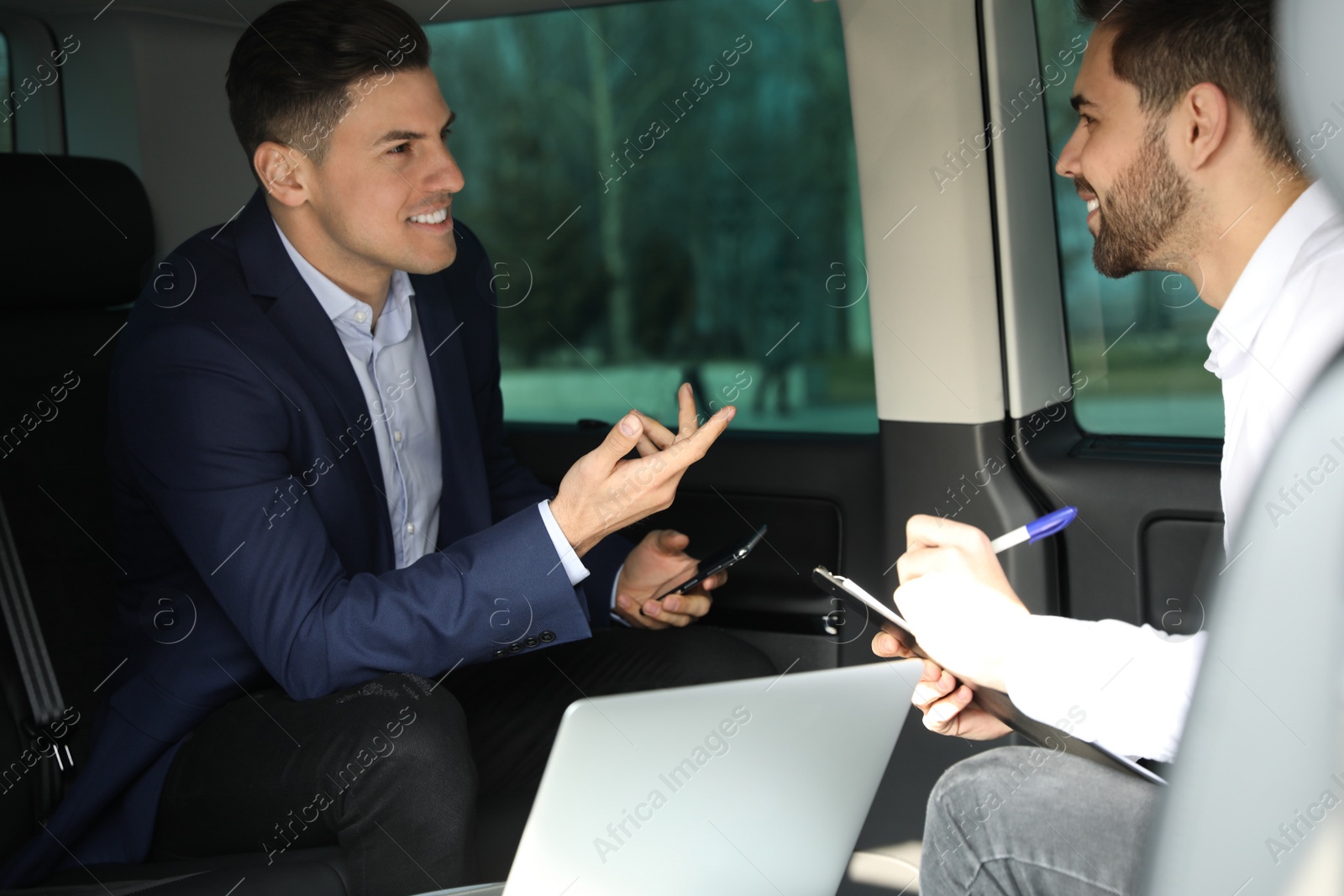 Photo of Businessmen working on backseat of modern car