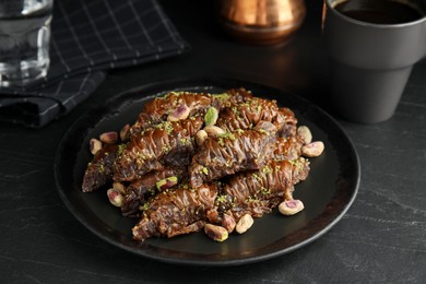 Photo of Delicious baklava with pistachio nuts on black table